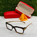 Cartier eyeglasses with a tortoiseshell frame and gold accents on a white surface, with Cartier cases in the background.