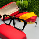Cartier eyeglasses with a black frame and gold accents on a white surface, with Cartier cases in the background.