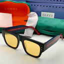 Black frames on a white surface, with Gucci branded accessories in the background.