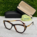 Tortoiseshell cat-eye glasses with Miu Miu case and pouch on a textured surface with grass background