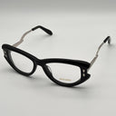 Black cat-eye glasses with silver accents on a light gray background