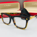 Cartier eyeglasses with a tortoiseshell frame and gold accents on a white surface, with Cartier cases in the background.