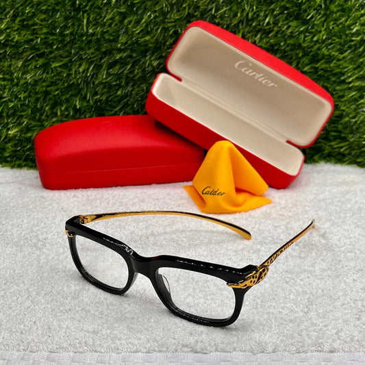 Black and gold eyeglasses with a red Cartier case on a white surface with grass background
