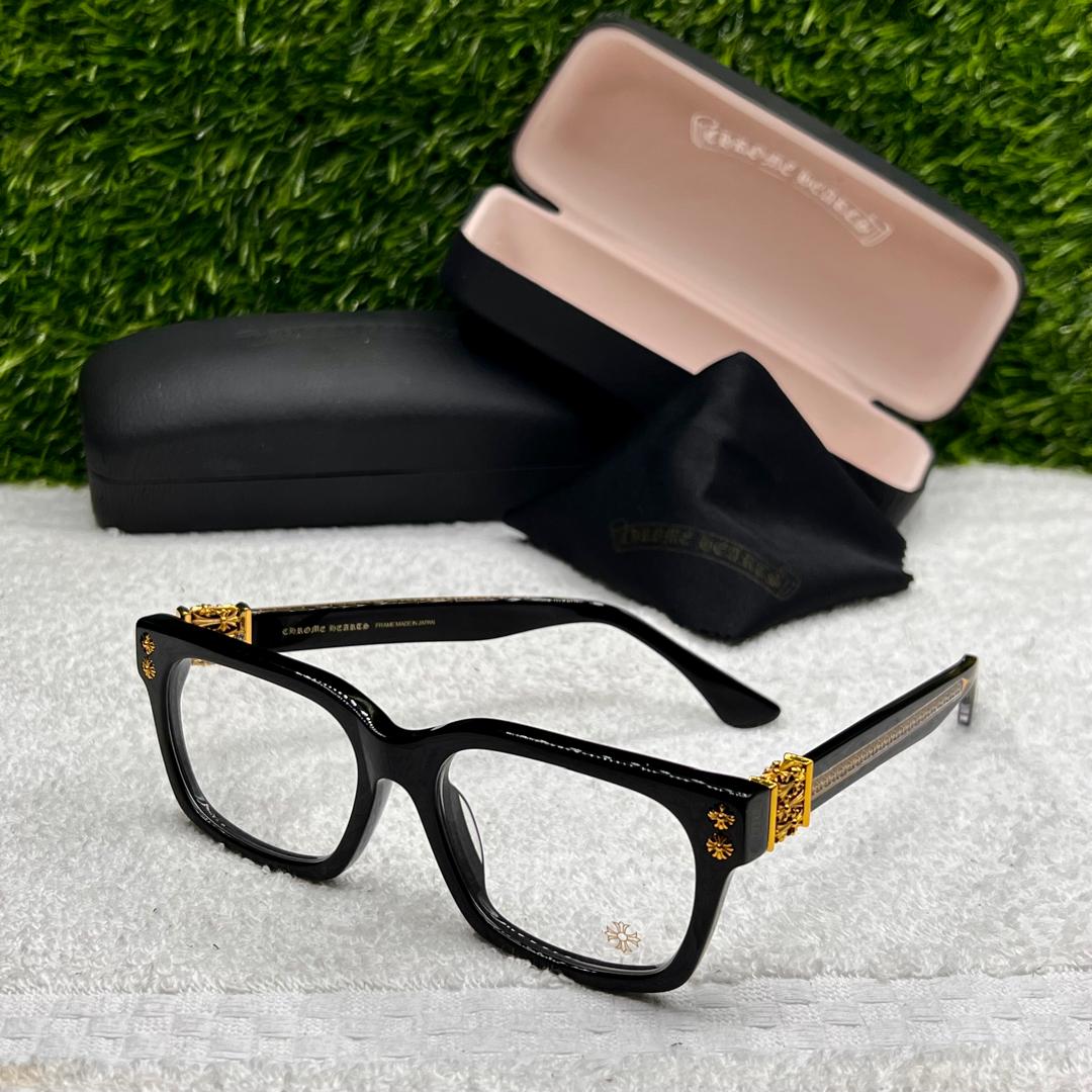 Black and gold eyeglasses with a case on a textured surface with grass background