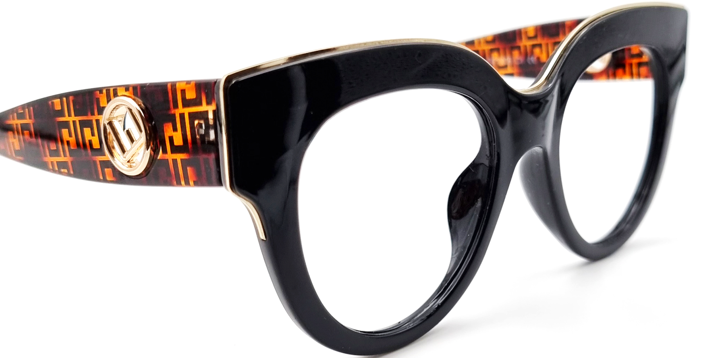 Large moulded, all-in-one, black frame glasses housing round lenses. Showing gold detail across the top of the frame and thick patterned arms with gold embellshment. side view with tinted lenses