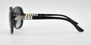 side view, large rounded rectangular black frame with tinted lenses. gold with 5 small gemstones detail on top part of the arm.