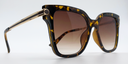 side view tortoiseshell rounded rectangular frame with small circular detail on front extending down the arms. Tinted lenses.