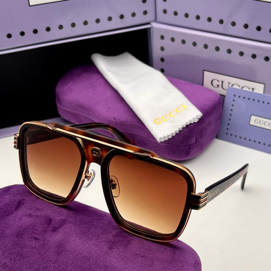 Brown sunglasses on a purple cushion with Gucci packaging in the background