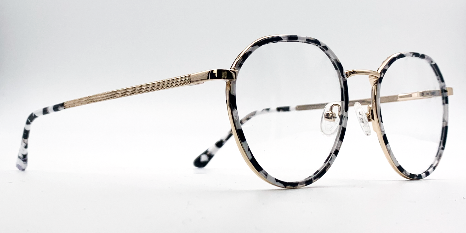 black and white round retro-style frame. Side view showing gold coloured bridge and arm